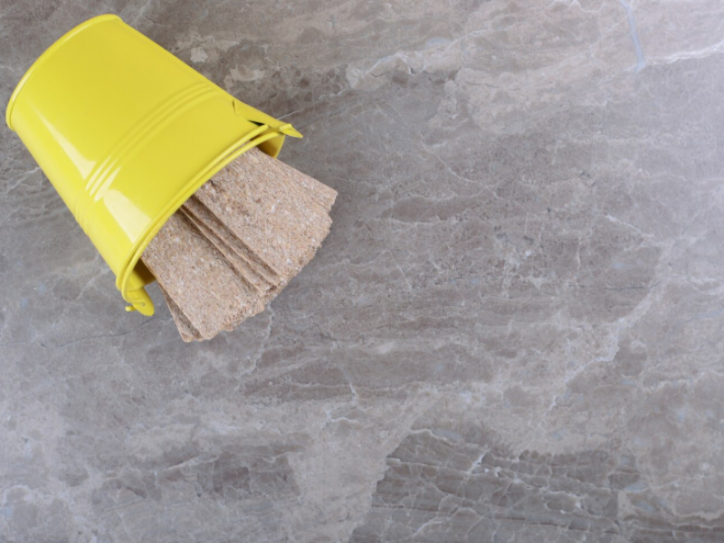 Yellow bucket tipped over on gray marble surface with whole grain crispbread spilling out in a casual, rustic scene.
